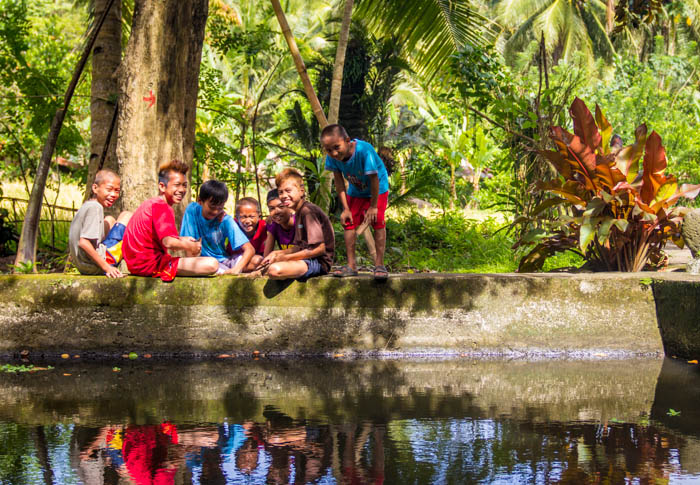 Some kids by the fish pond having a good time.